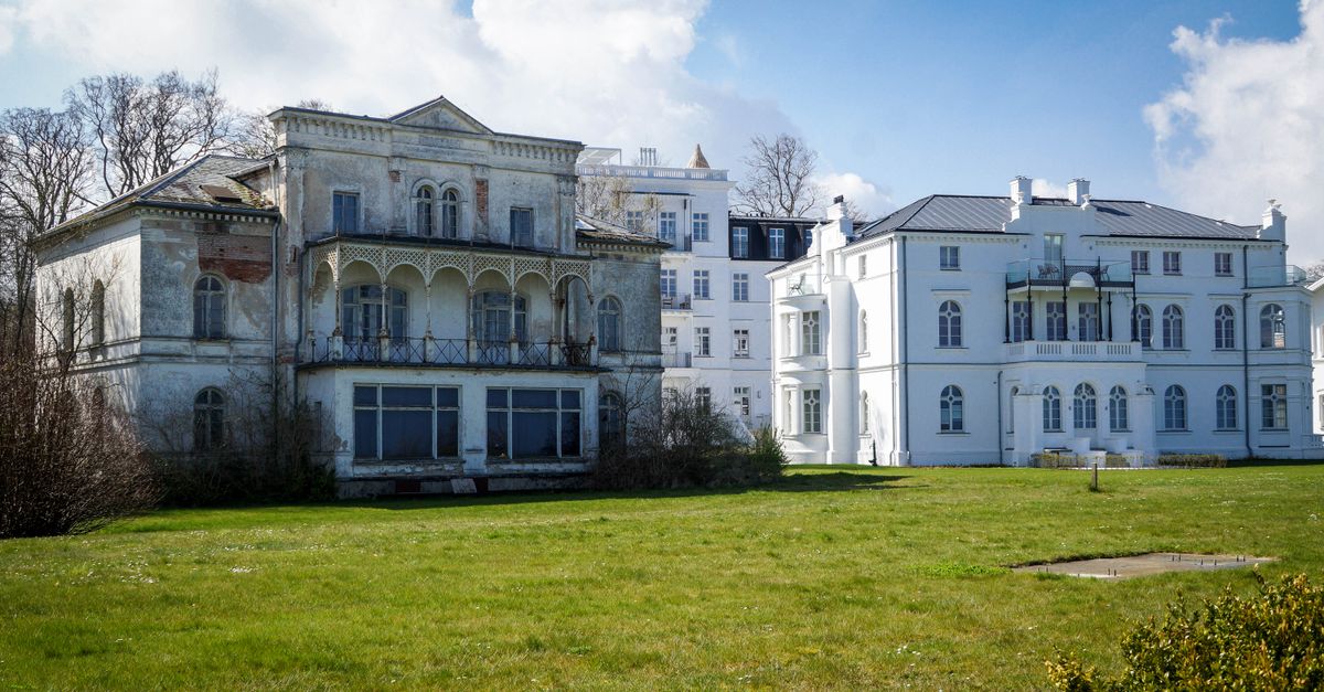 An old mansion contrasts against a modern building in a sunny landscape.