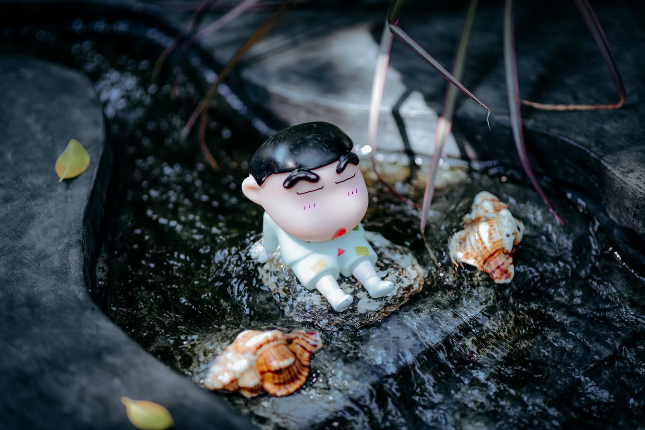 charming anime figurine resting in a garden water feature with seashel