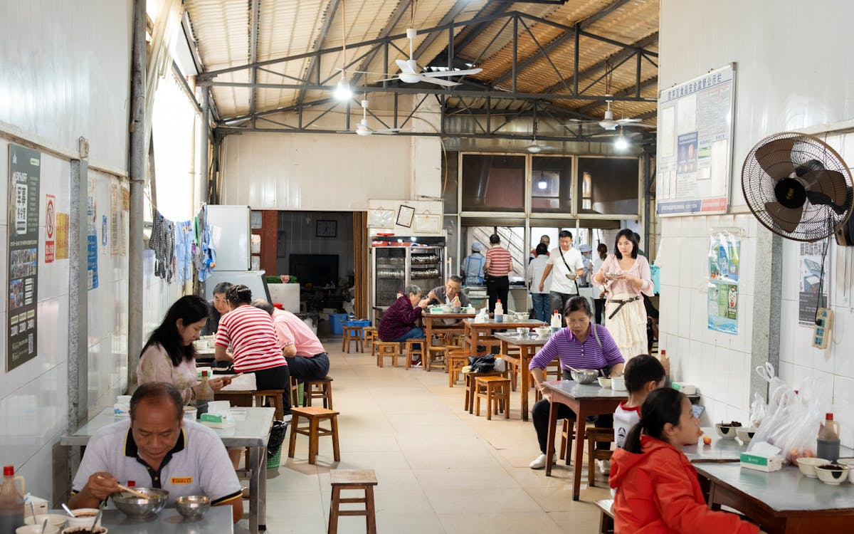 Customers enjoying a meal at a bustling eatery in Yunnan, China. Capturing local dining culture.
