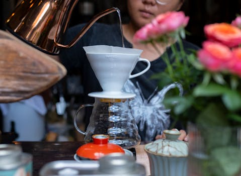 Close-up of pour-over coffee brewing in a Yunnan cafe, surrounded by vibrant flowers.