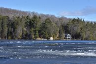 Tranquil lake with icy waters and forest backdrop on a clear winter day.