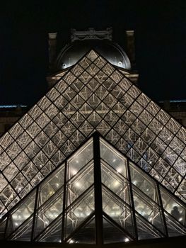 Stunning view of the Louvre Pyramid beautifully lit against the night sky in Paris.