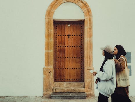 Candid street shot of two women passing a traditional Moroccan wooden door in Rabat.