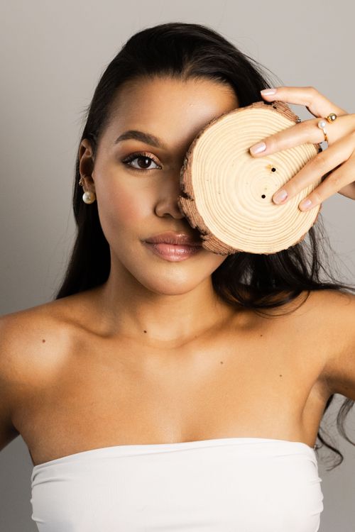 Free Elegant portrait of a woman holding a wooden piece over her eye, embodying modern fashion. Stock Photo