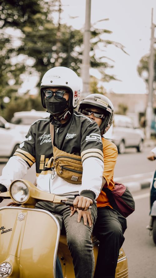 Free Couple riding a Vespa scooter through East Java's vibrant streets, capturing local culture. Stock Photo