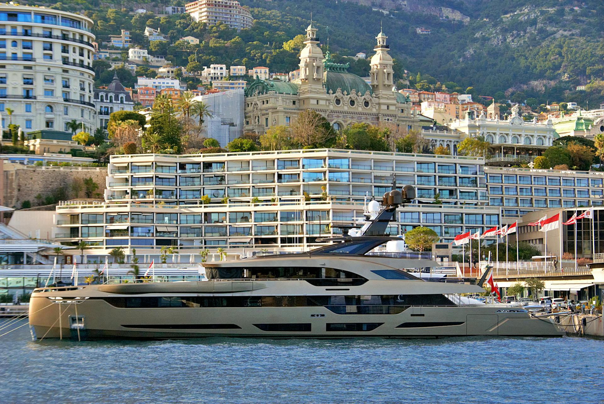 Luxurious yacht docked at Monte Carlo Harbor with elegant Monaco architecture in the background.