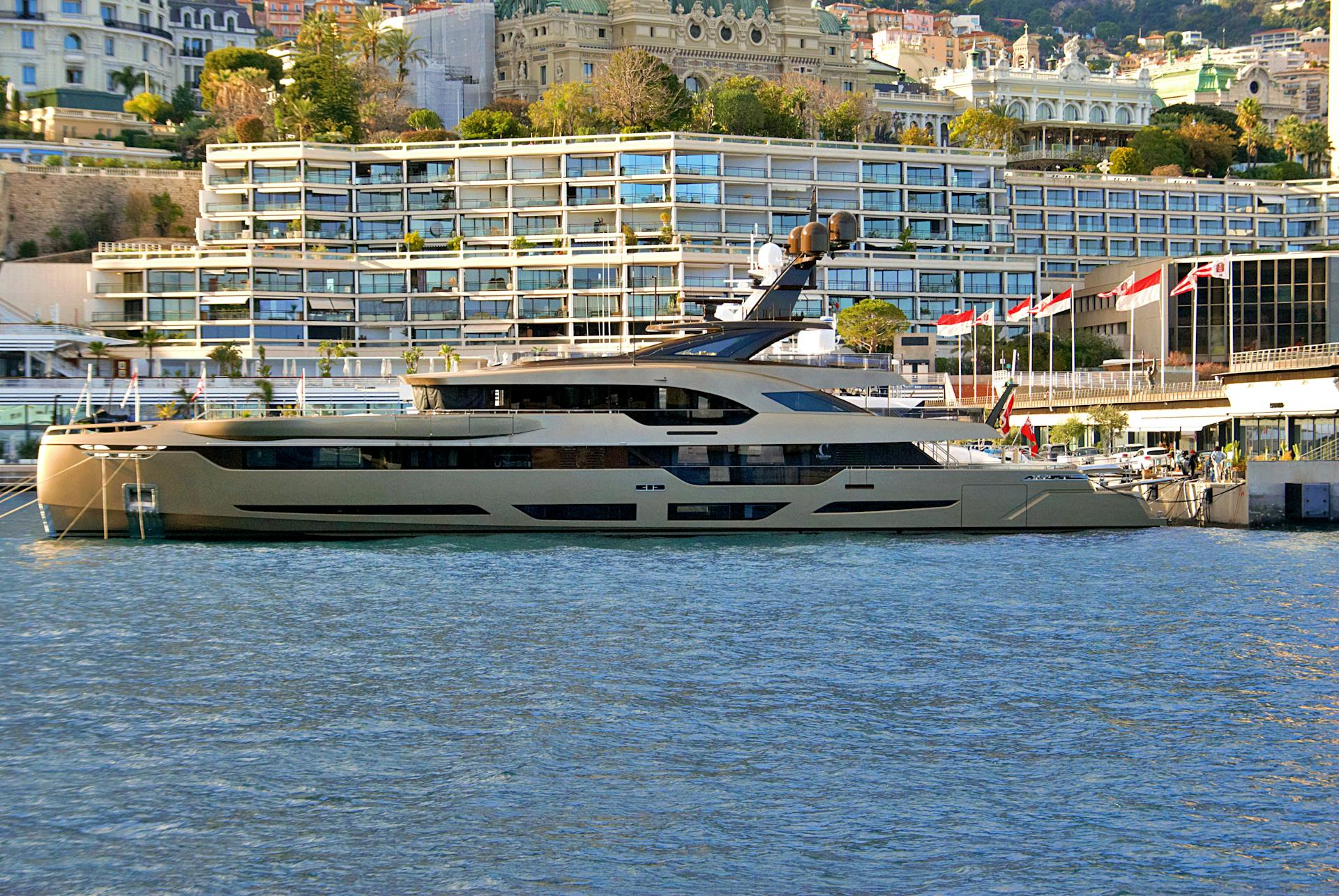 A luxury yacht moored at the picturesque Monaco harbor with modern waterfront architecture.