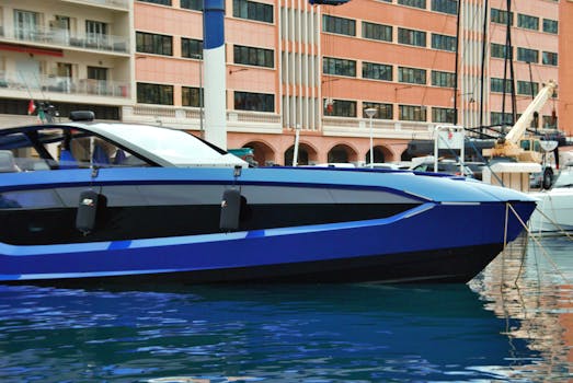 Sleek blue luxury yacht docked in Monaco's harbor with scenic architecture in view.
