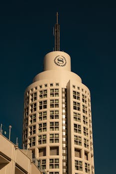 Tall modern high-rise building under a clear blue sky, showcasing architectural style.