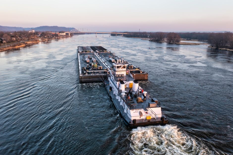 Aerial view of a cargo barge navigating the Mississippi River near Wabasha, Minnesota at sunset.