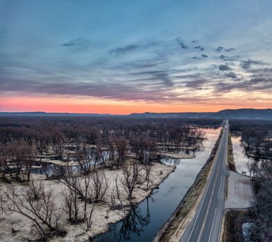A breathtaking aerial view of a winding river and road during a vibrant sunset in Nelson, Wisconsin.