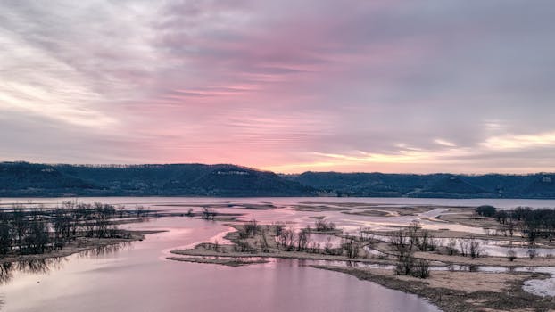 A peaceful sunrise over the Mississippi River with calm waters and pastel skies near Nelson, Wisconsin.