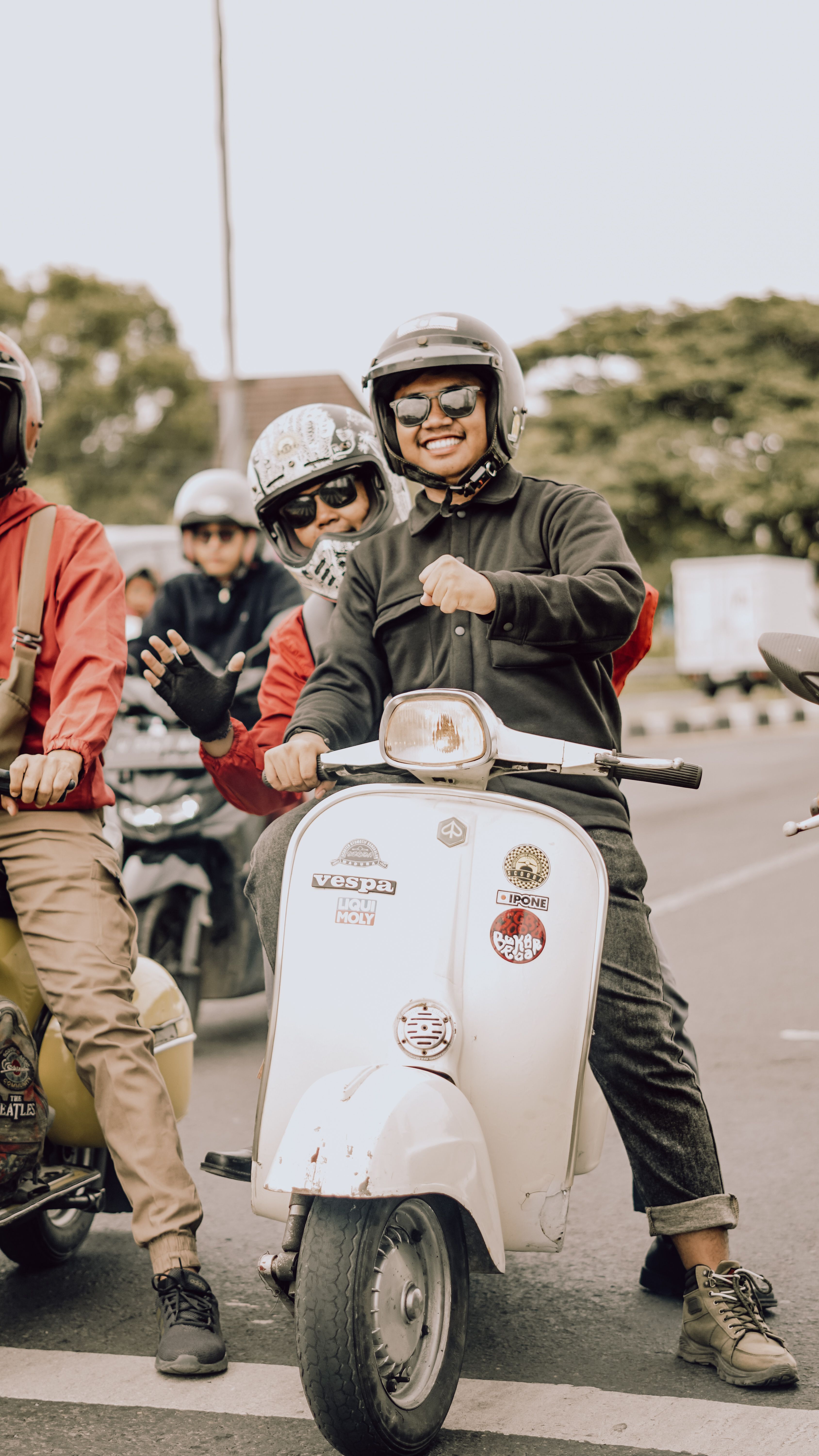 A lively group of friends enjoying a Vespa ride on the streets of East Java, Indonesia.