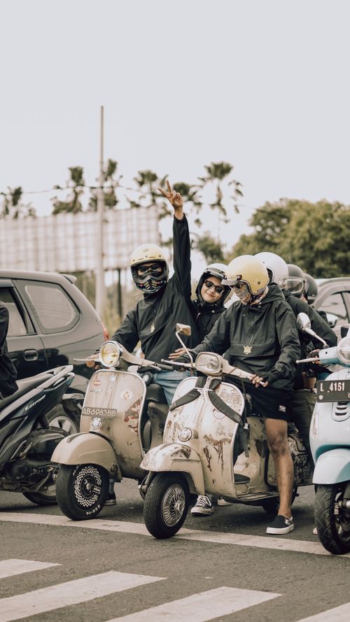Free Group of friends riding vintage Vespas outdoors in East Java, Indonesia, enjoying a sunny day. Stock Photo