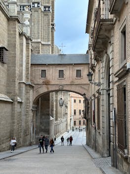 Historic street view in Toledo, Spain, featuring architectural stone buildings and archway.
