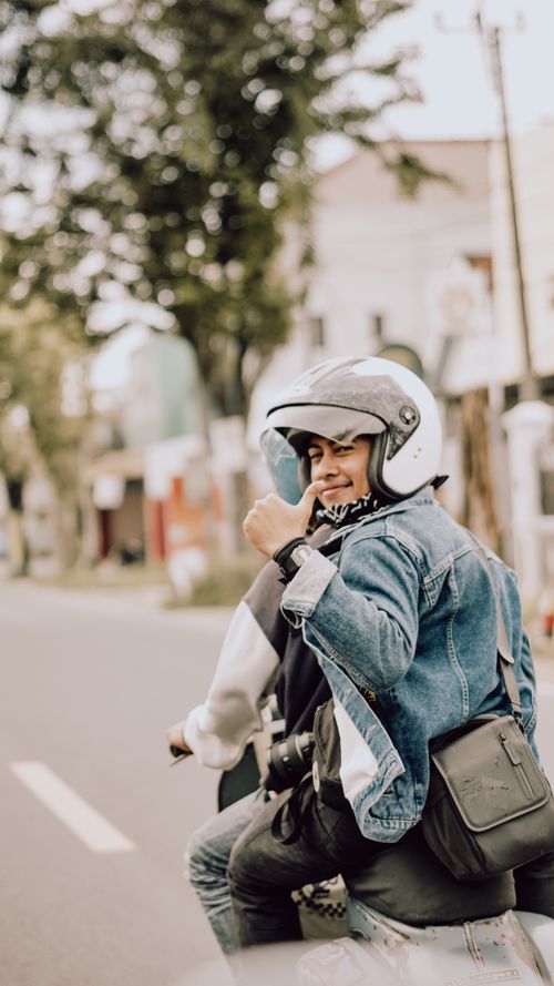 Free Young rider in denim jacket and helmet giving thumbs up on scooter in East Java. Stock Photo