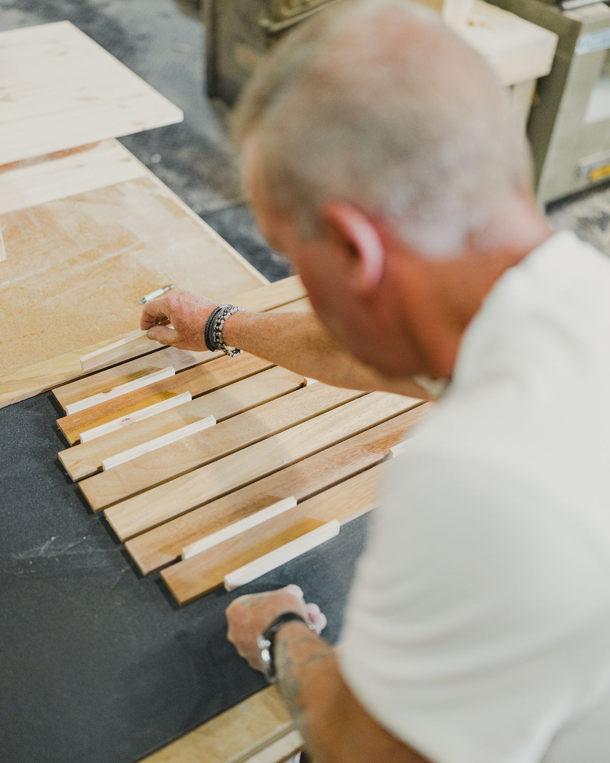 Solid vs. Engineered Hardwood Flooring: 2026 Guide 7 Wood craftsman aligning multiple natural wood slats with precision