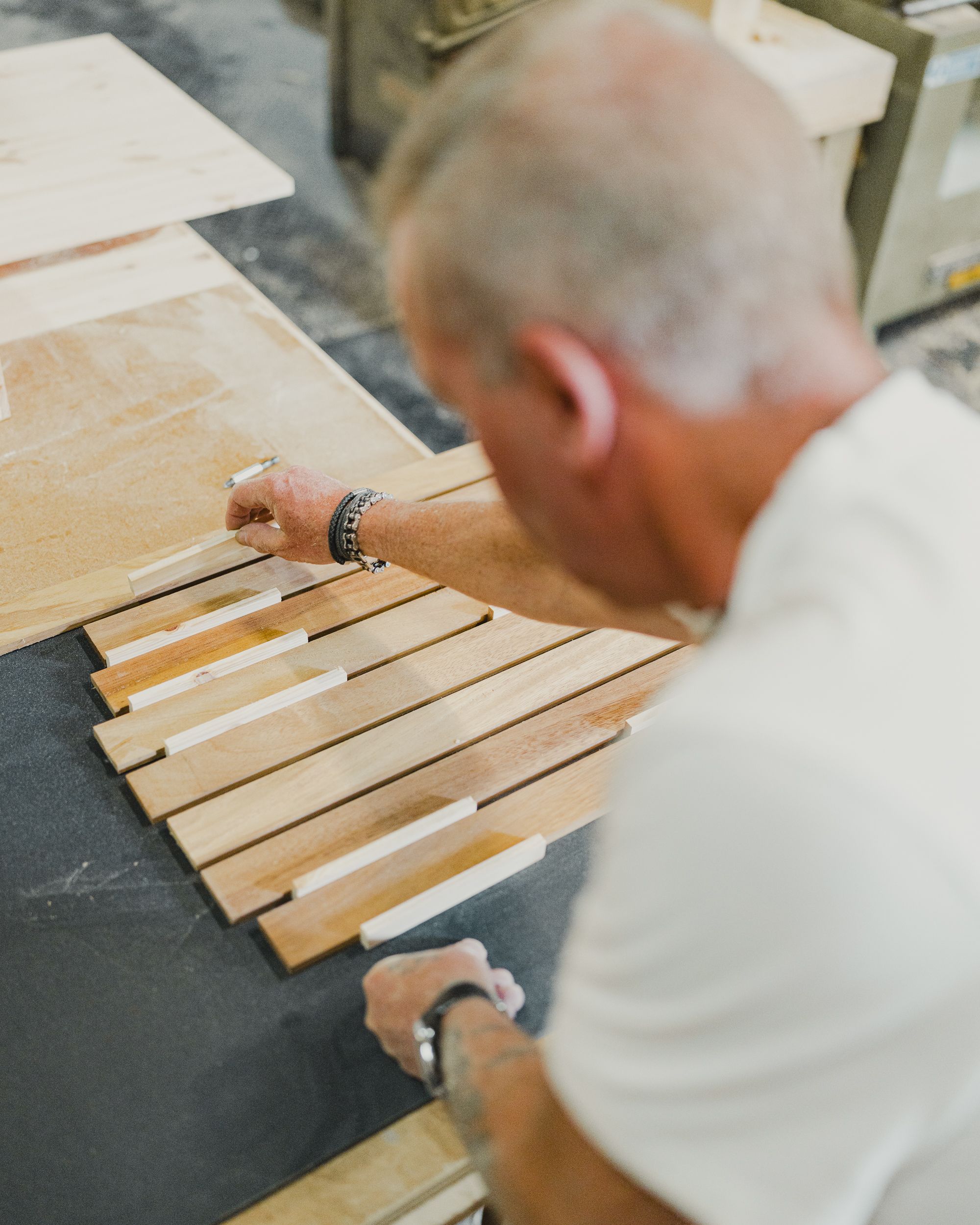 Craftsman aligning wooden slats in a workshop — photo by shoreline vehicles