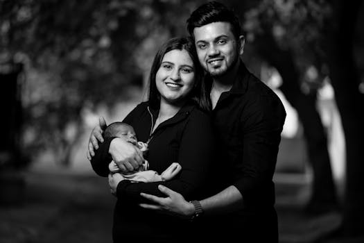 Heartwarming black and white photo of a young couple with their newborn outdoors.