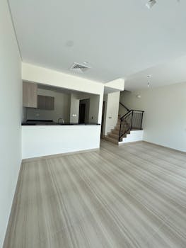 Empty contemporary living space with open kitchen and stairs.