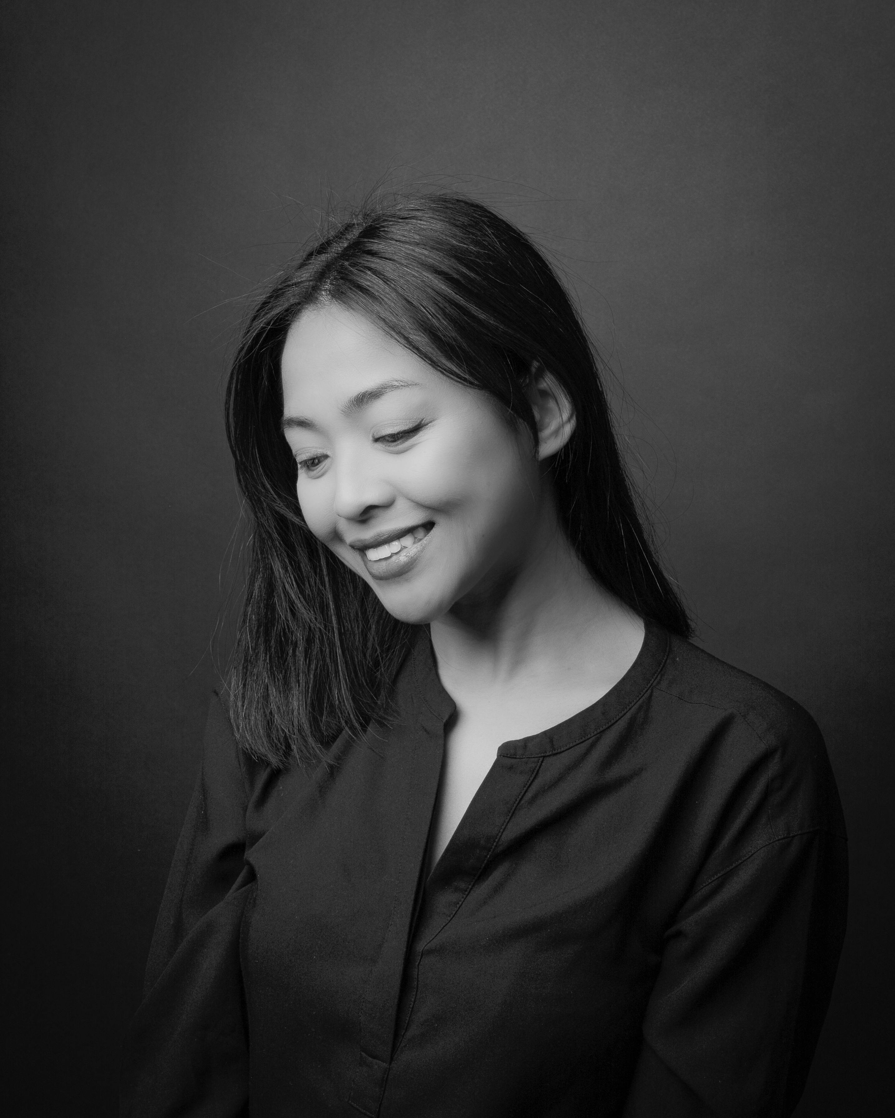 A beautiful black and white portrait featuring a smiling woman in a serene and elegant pose.