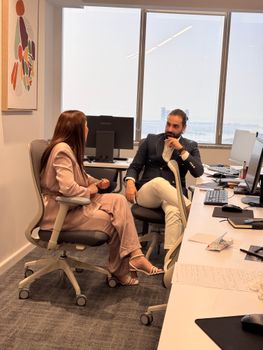 Two colleagues engaged in a discussion in a modern office setting.