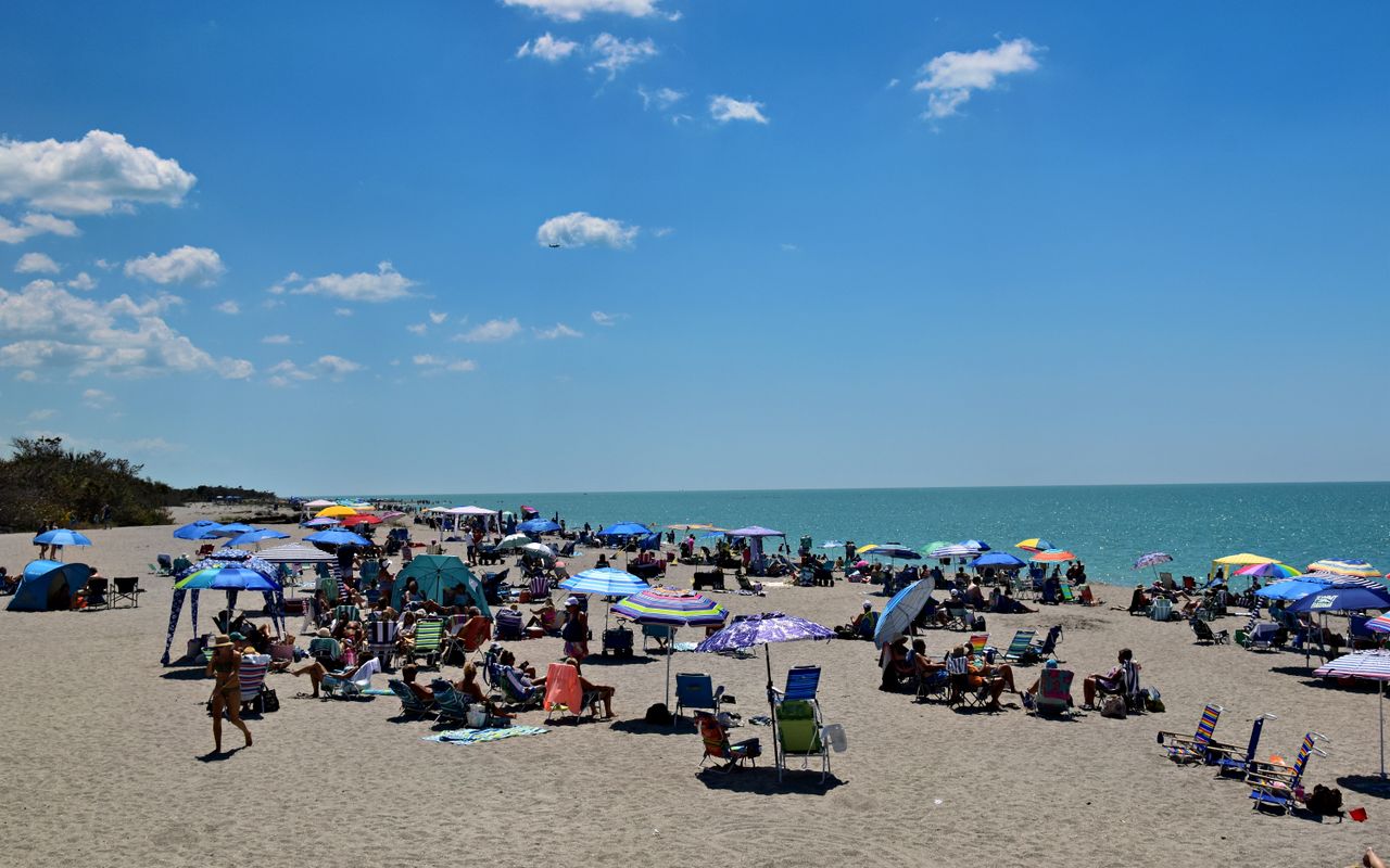 Crowded beach with colorful umbrellas in Venice, Florida.