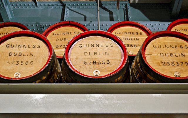 Photo: Renata Moraes on Pexels Wooden barrels labeled 'Guinness Dublin' in a museum setting showcasing Irish brewing history.
