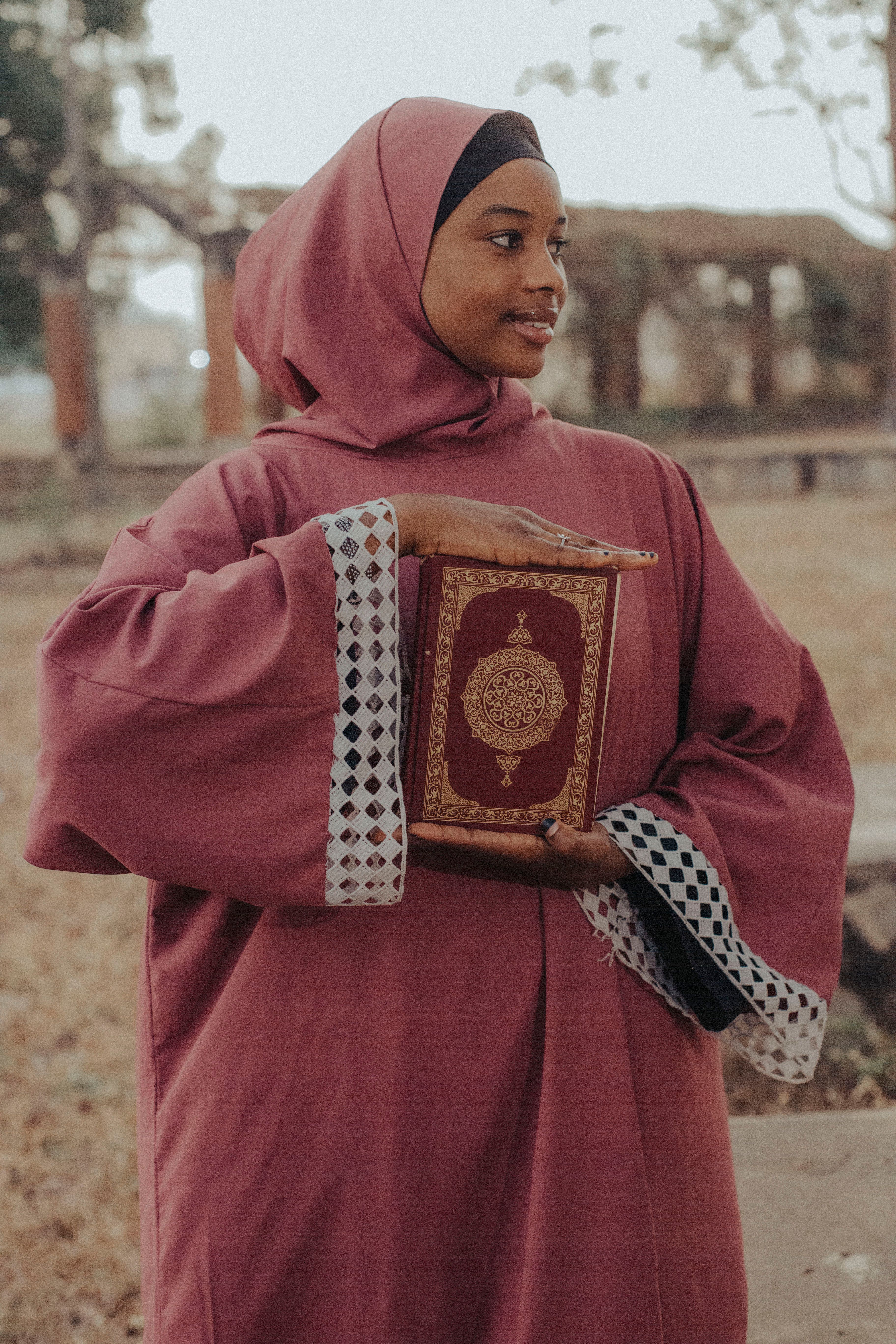 Woman in Hijab Holding Quran Outdoors · Free Stock Photo
