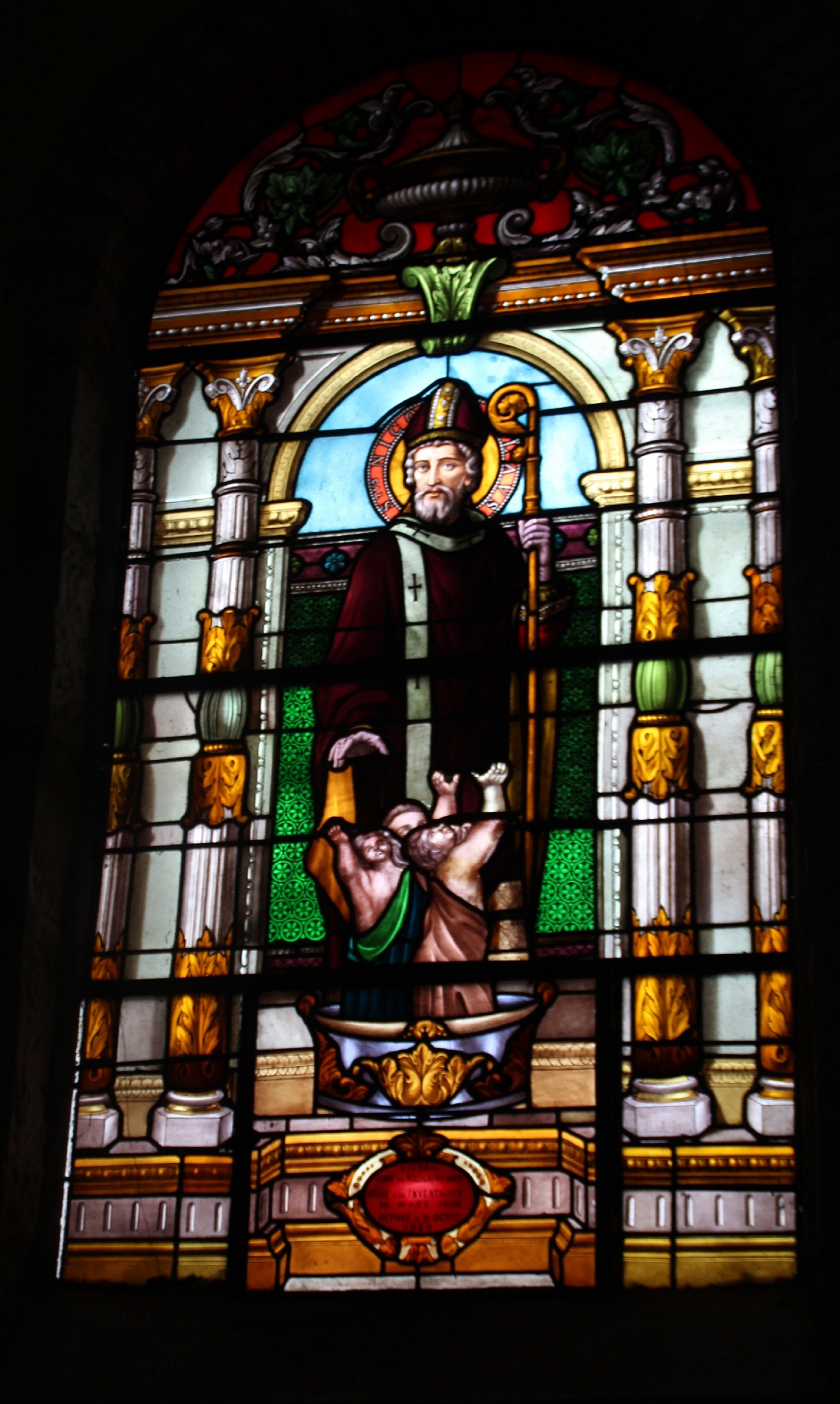 Beautiful stained glass window depicting a religious figure inside a French church.