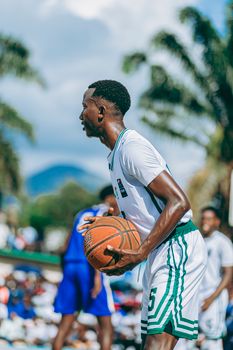 Young athlete playing basketball outdoors in a competitive game setting.