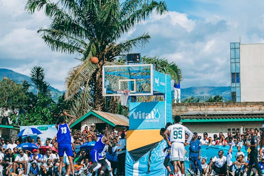 Vibrant outdoor basketball game with athletes and spectators under sunny skies in Africa.