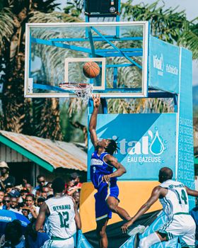 Dynamic street basketball game with players jumping near hoop outdoors.