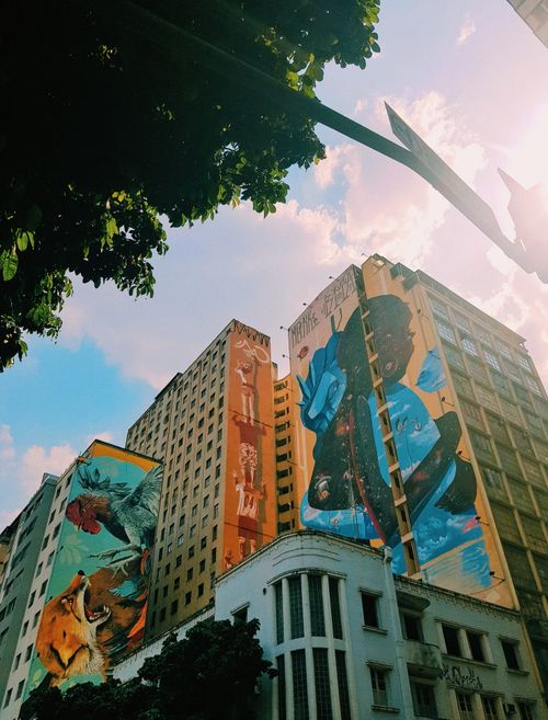 Free Vibrant street art murals on skyscrapers showcasing urban creativity and architectural beauty. Stock Photo