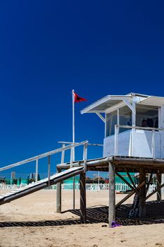 A bright lifeguard tower on Mar del Plata beach with a red flag and clear blue sky.