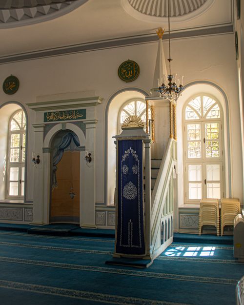Free Elegant mosque interior featuring ornate decor and sunlight through arched windows. Stock Photo