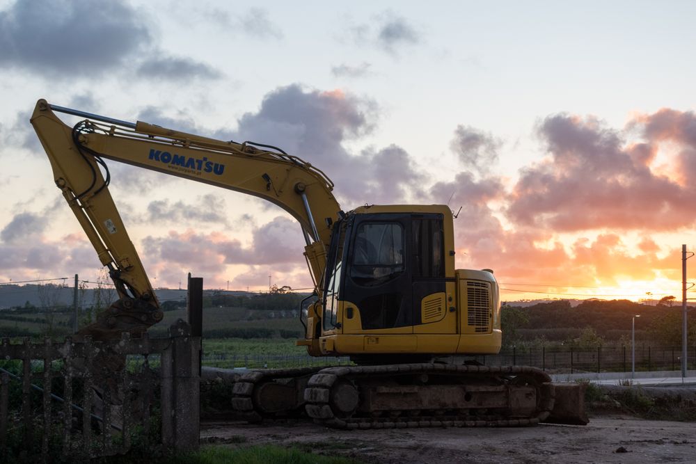 Silhouette of an excavator working at sunset on a construction site
