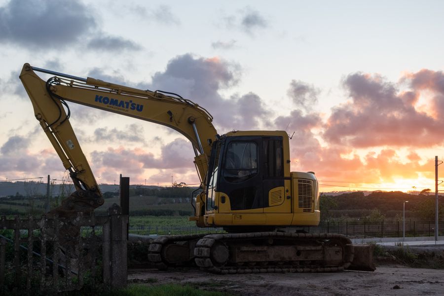 Yellow excavator parked at a job site at sunset