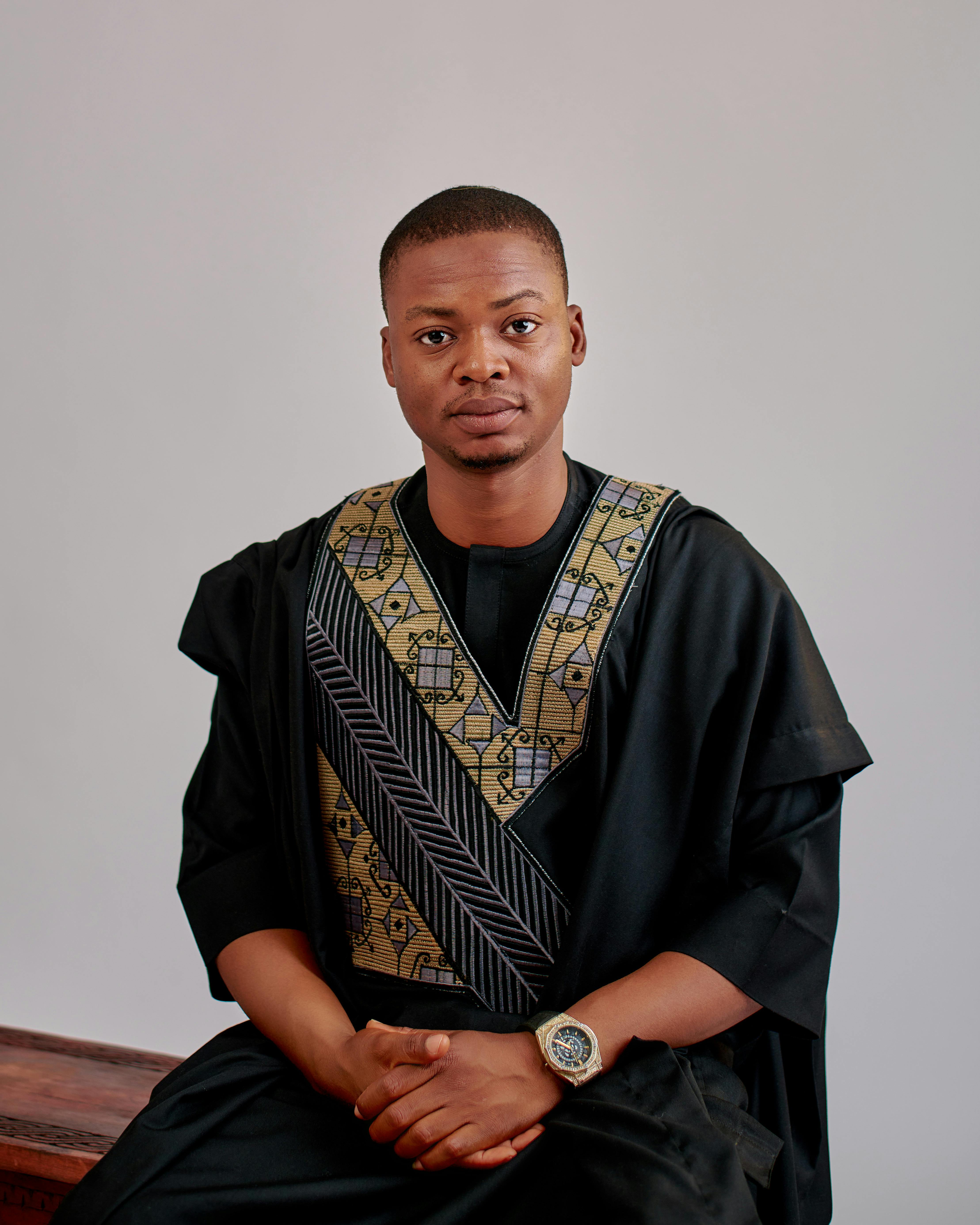 Elegant portrait of a man in traditional black attire with intricate patterns.