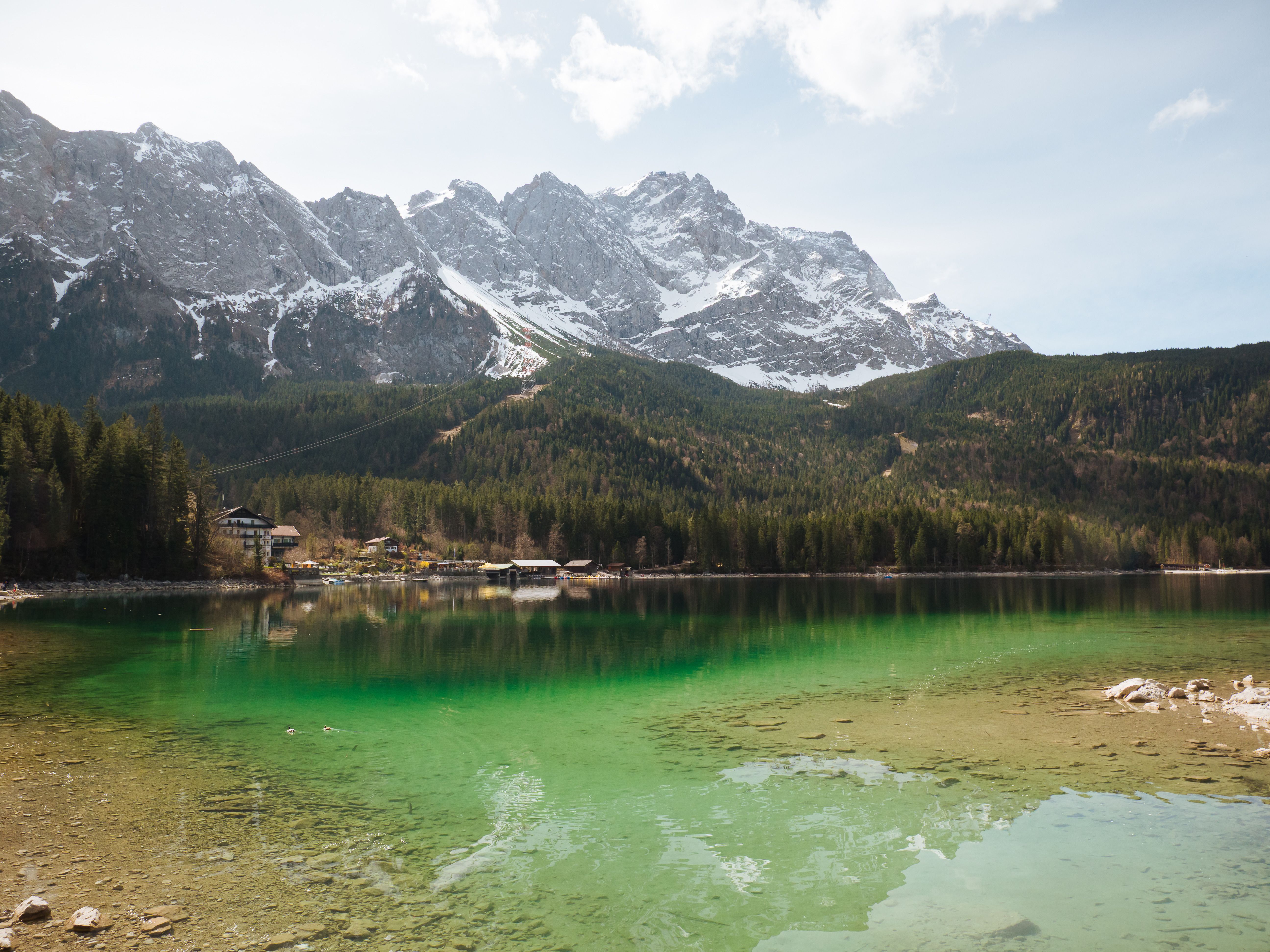 Blick auf den Eibsee mit klarem smaragdgrünem Wasser und die schneebedeckte Zugspitze im Hintergrund