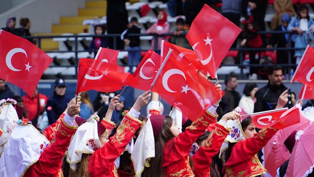Children in traditional costumes wave Turkish flags at a National Festival in İstanbul.