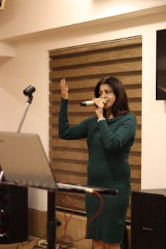 South Asian woman singing indoors using a microphone during an event in Ahmedabad, India.
