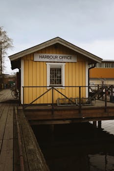 A picturesque yellow wooden harbour office by the calm Stockholm waterside.