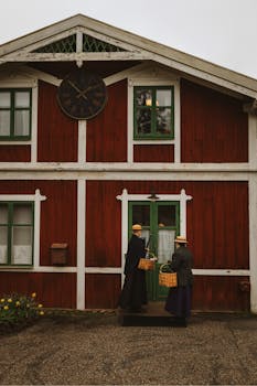 Historical Swedish house with two people in traditional outfits and baskets, offering vintage appeal.