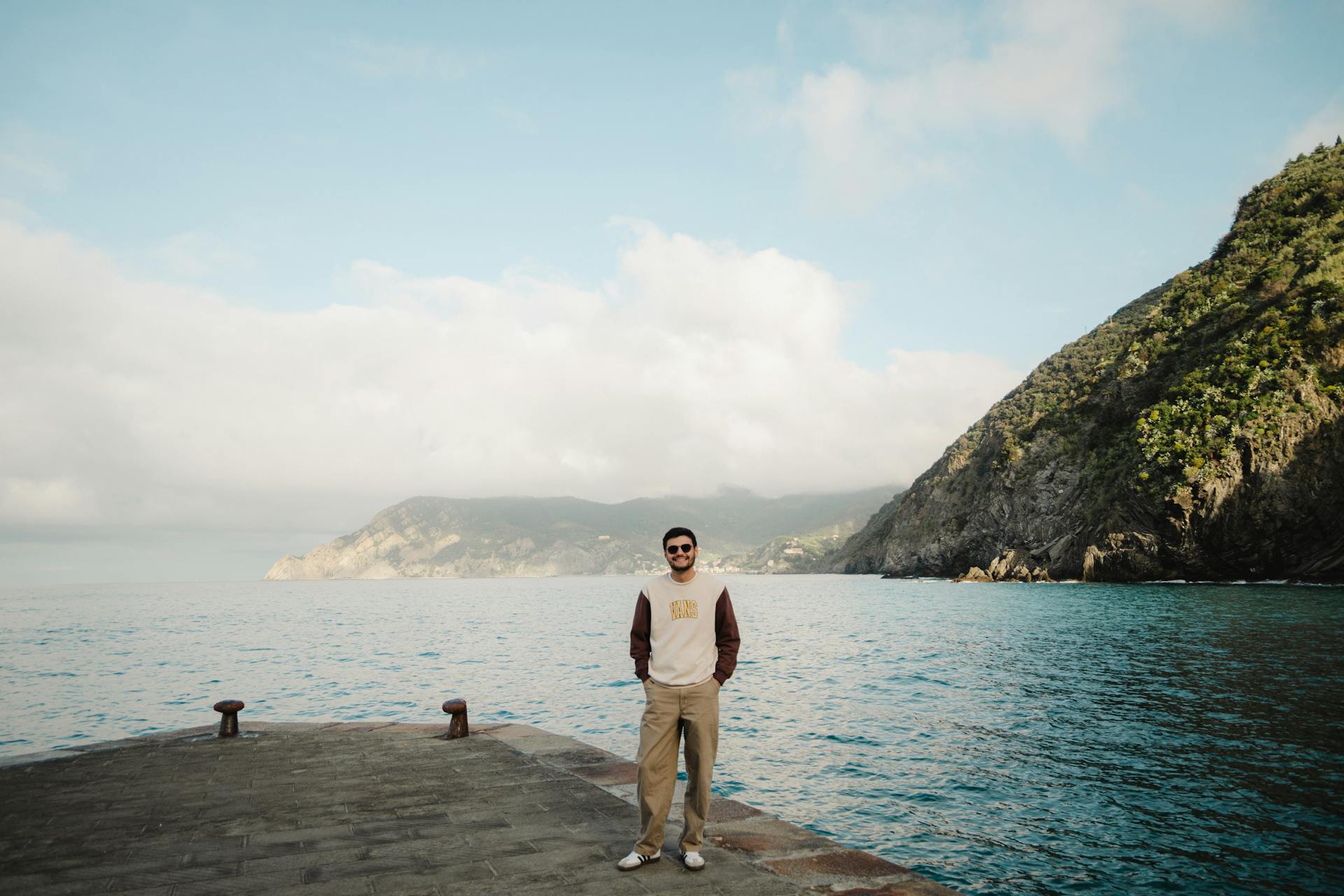 Young man on pier with stunning coastal views and clear skies.