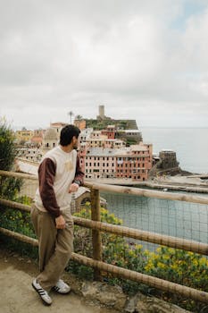 Man overlooks picturesque Vernazza in Cinque Terre, Italy, with colorful buildings by the sea.