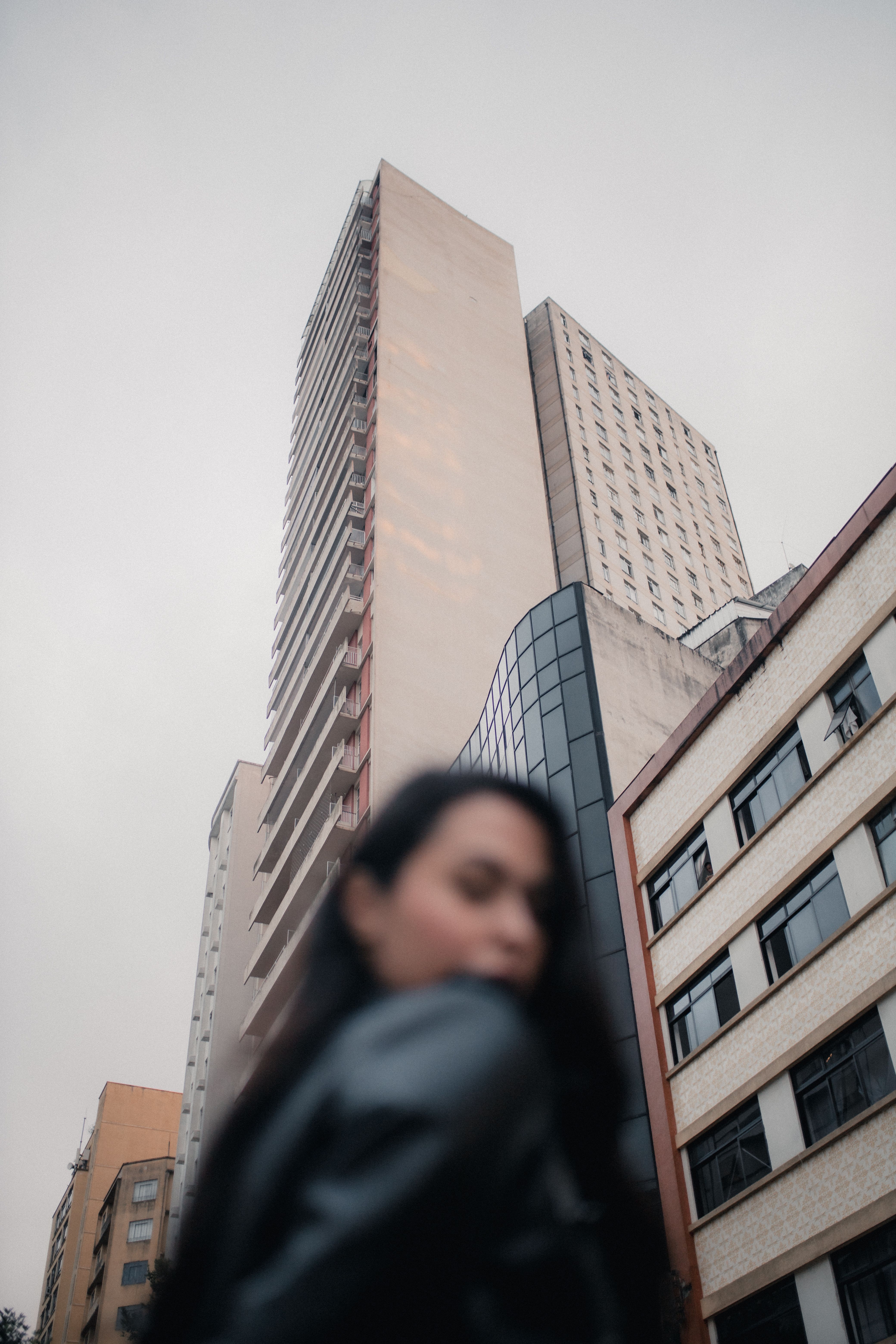 Blurry foreground of a person against towering modern skyscrapers in a city setting.