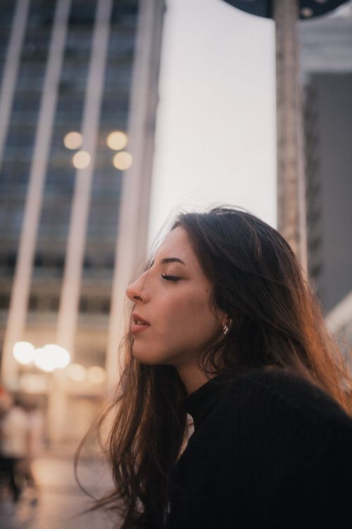 Free Profile of a woman in a cityscape during twilight, surrounded by tall buildings. Stock Photo