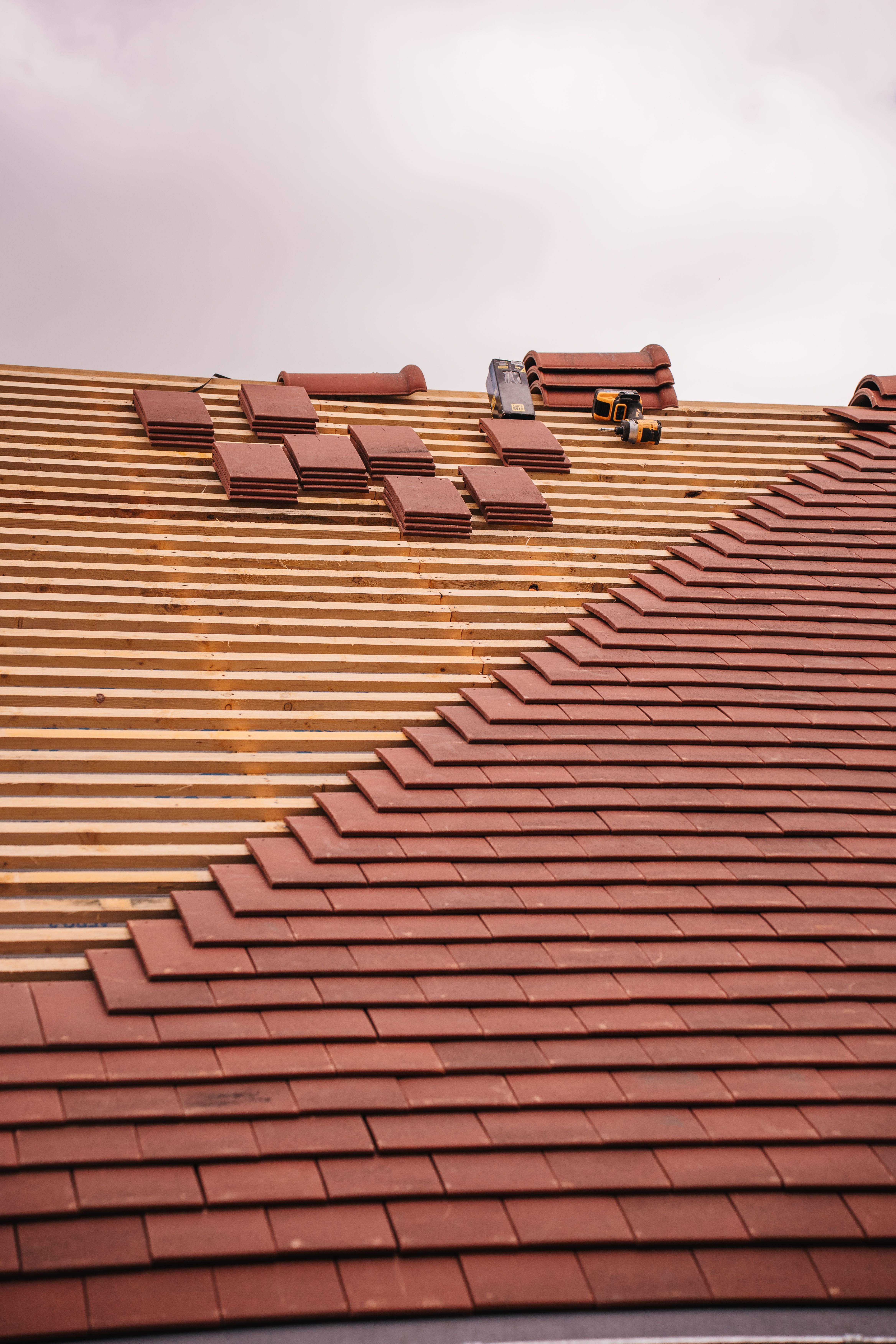 gratis Gedeeltelijke installatie van een terracotta dakpan op een gebouw in uitvoering. Stockfoto