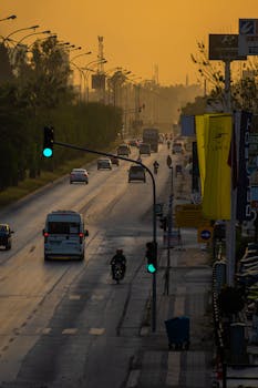 An urban street with vehicles at sunset, showcasing vibrant city life and atmospheric lighting.